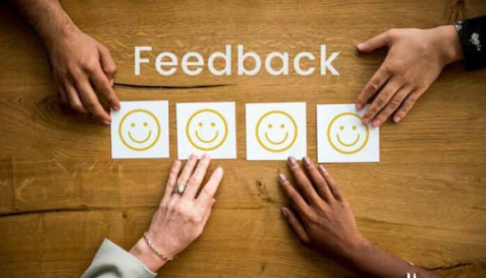 Hands placing smiley face cards in front of the word Feedback for client-side commenting system visual feedback