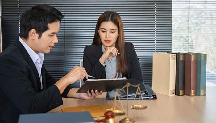 A lawyer reviewing documents with a client in an office setting, discussing legal strategy and steps that can help achieve a strong settlement offer in a personal injury case.