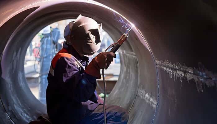 Welder inside a large pipe using laser welding machines, showcasing the capability of laser welding for intricate work and tight spaces in professional applications