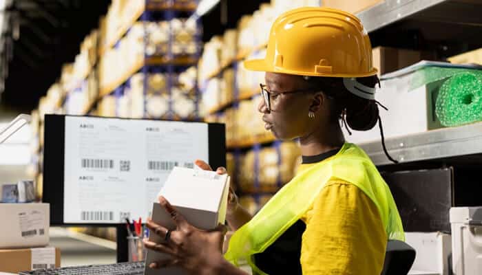 Worker using a Barcode Inventory System to verify product details and manage inventory in a warehouse.