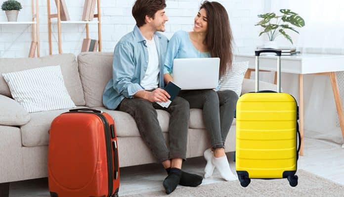 Couple planning their vacation with laptops and suitcases, highlighting tour package advantages like easy planning and bundled travel services.