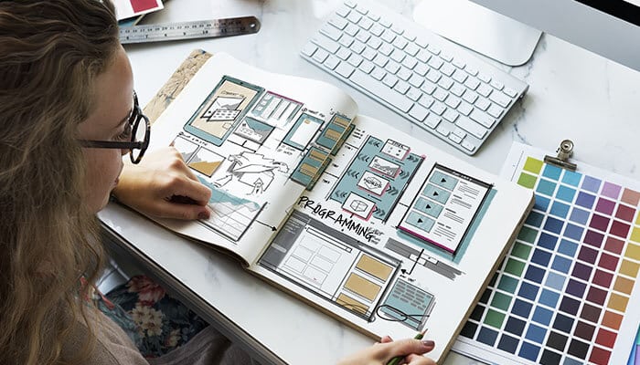 Designer planning layouts and color palettes while exploring web design trends for modern, user-focused websites.