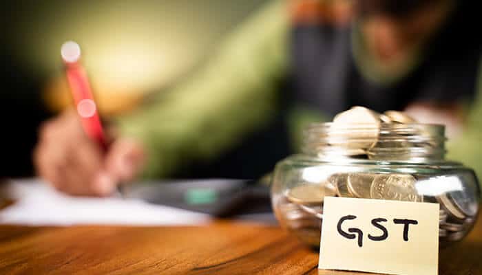 GST jar with coins and a financial calculator, symbolizing the role of debit note and credit note in GST tax adjustments for businesses.