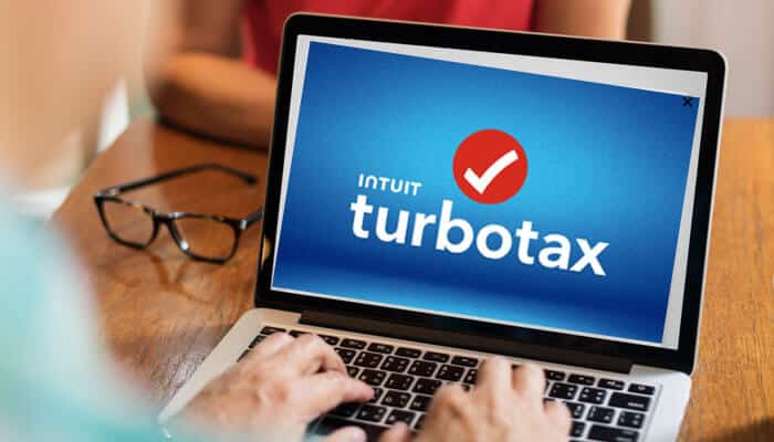 Person using TurboTax on a laptop, highlighting the software for tax filing, in a comparison with FreeTaxUSA.