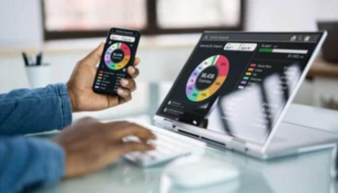 A person using a budgeting app on their phone and laptop to track spending and financial goals showcasing the best budgeting apps