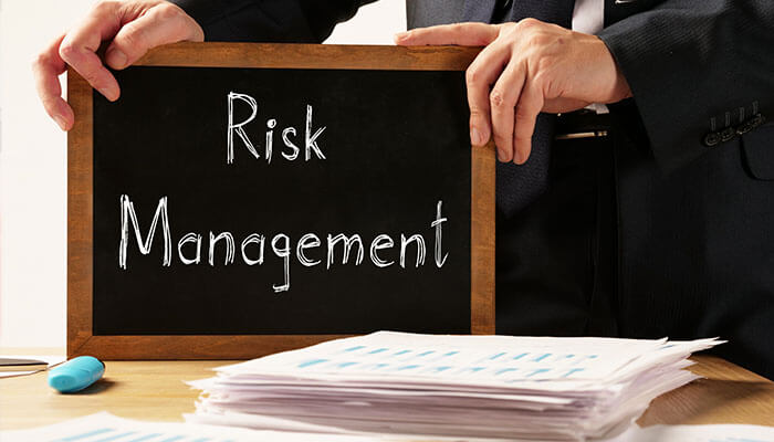 Risk Management Strategies - Startupeditor | Startup Editor A business owner holding a chalkboard with Risk Management written on it, emphasizing the importance of managing employee car accidents