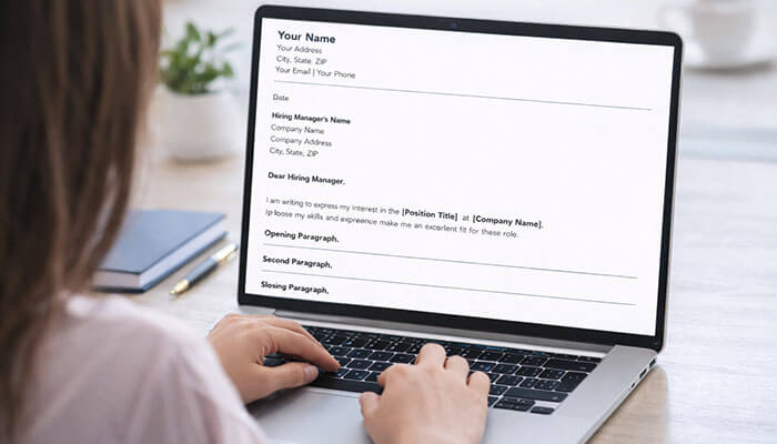 Step-by-Step Guide to Writing a Cover Letter - Startupeditor | Startup Editor Close-up of a woman typing on a laptop with a free cover letter template visible, showing the structure of a personalized cover letter.
