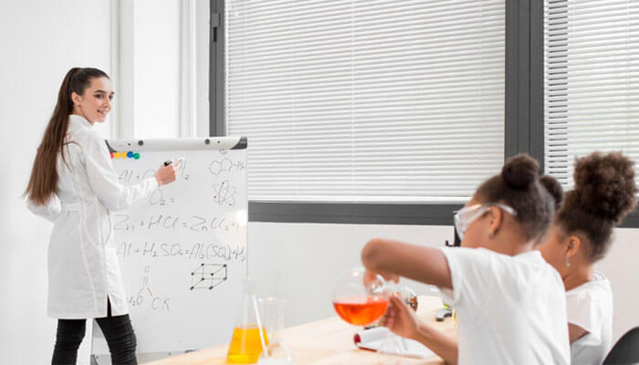 Educational Theories and Teaching Strategies - Startup Editor | Startup Editor Educator demonstrating science concepts to students during a laboratory activity, illustrating teaching strategies covered in an Online MSN Nurse Educator Program