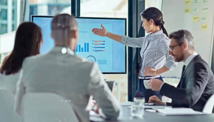 Environmental Scan in a corporate meeting showing a business team analyzing performance dashboards on a digital screen, with a presenter explaining data trends, market insights, and strategic indicators used for organizational decision-making and environmental analysis.