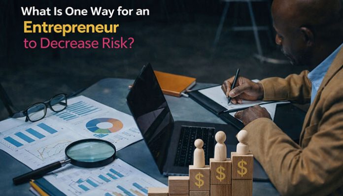 What is one way for an entrepreneur to decrease risk? Entrepreneur reviewing financial charts and data to make informed decisions and reduce business uncertainties.