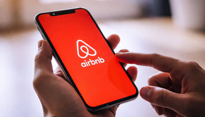 Benefits of Using Airbnb Account Software - Startupeditor | Startup Editor Airbnb account software mobile app on smartphone used for managing bookings and guest communication on the go