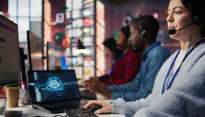 Customer support team wearing headsets works at computers in a modern call center.