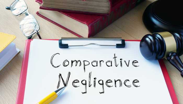 How Colorados Modified Comparative Fault Works | Startup Editor Clipboard on a desk with the words 'Comparative Negligence' written on paper, surrounded by a pencil, gavel, glasses, and books—legal study setup.