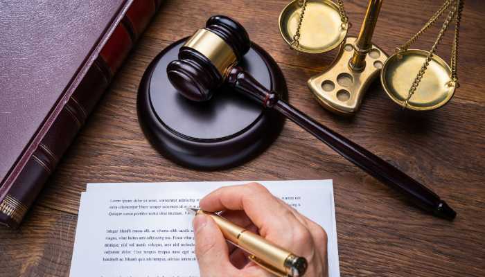 The Three-Year Statute of Limitations and What It Actually Allows | Startup Editor Gavel and scales of justice on a wooden desk, with a hand signing a document nearby.