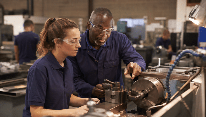 15 Benefits of Apprenticeships for Employers | Startup Editor Benefits of apprenticeships for employers with a supervisor training an apprentice on industrial machinery.