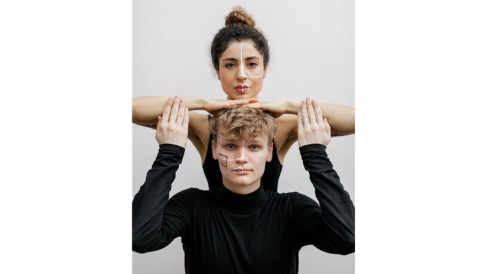 Creative Marketing Ideas Using Face Swap | Startup Editor Two people in black, stacked pose: the front person faces the camera with chalk lines on the cheeks while the back person rests their forearms over the front person’s head to frame the shot.