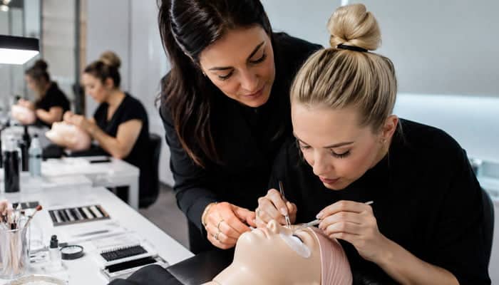 Choosing the Right Path for Your Career - Startupeditor 1 | Startup Editor Beauty students practice eyelash extensions on a mannequin head as an instructor guides the process in a salon classroom.