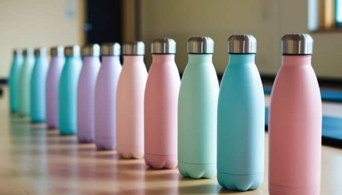 Designing Premium Bottles - Startupeditor | Startup Editor Row of pastel-colored stainless steel water bottles with silver caps lined up on a table.