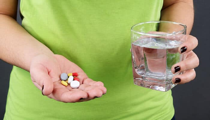 Can You Take Acetaminophen With BI 8? - Startup Editor | Startup Editor BI 8 White Pill medication safety concept showing a person holding assorted pills with a glass of water before taking medicine.