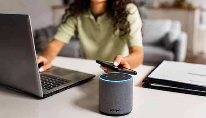 Historical Alexa for Business Pricing - Startup Editor | Startup Editor Amazon Alexa Business Echo device beside a laptop and smartphone, illustrating voice-assisted productivity and connected workplace technology.