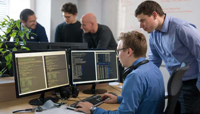 Is Zenvekeypo4 Workflow Automation Software? - Startup Editor | Startup Editor Zenvekeypo4 Software Explained with a development team reviewing code on multiple monitors while troubleshooting software and technical issues.