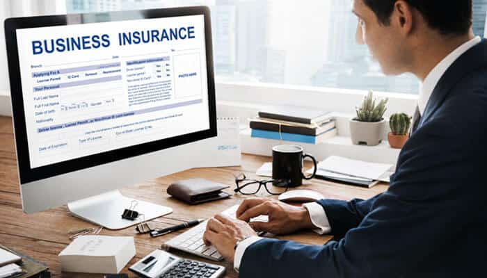 Types of Startup Business Insurance at a Glance - Startup Editor | Startup Editor Startup Business Insurance application being reviewed online by a business owner at an office desk.