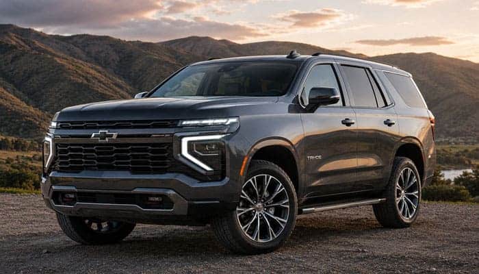 What Is New on the 2027 Chevy Tahoe - Startupeditor | Startup Editor 2027 Chevy Tahoe dark gray SUV parked in a mountain landscape at sunset.