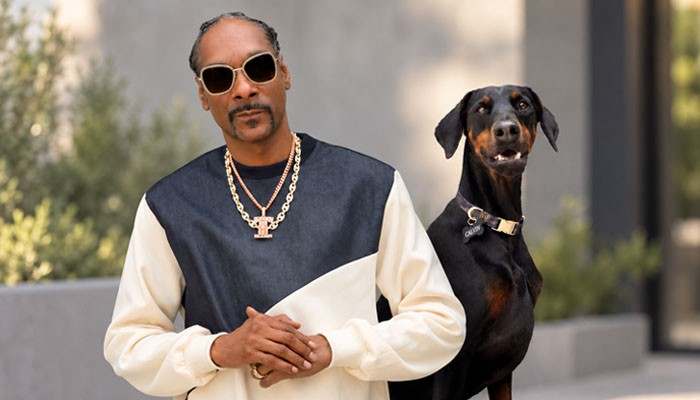 How Snoop Dogg Built His Fortune - Startup Editor | Startup Editor Snoop Dogg Net Worth 2026 image featuring Snoop Dogg with a Doberman, highlighting the personal brand and cultural identity behind his long-running music and entrepreneurial career.