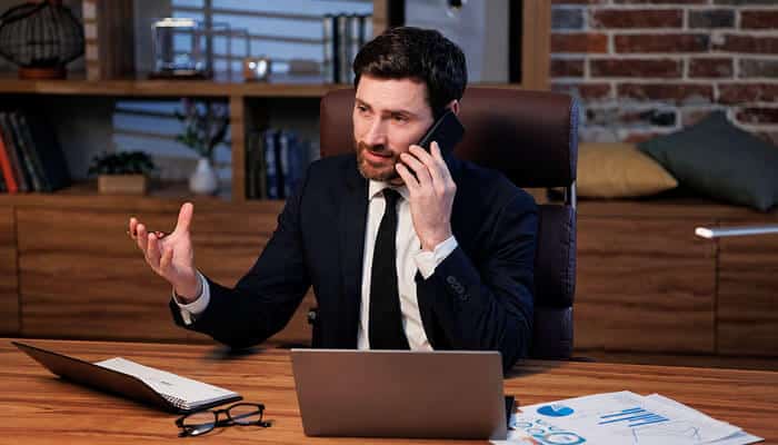 How to Verify a Financial Professional - Startup Editor | Startup Editor Finance professional using a laptop and phone, representing research into Kenneth MyGreenBucks .net financial and business claims.