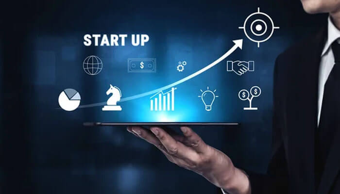 Does Every Startup Need Venture Capital? - Startup Editor | Startup Editor Hands holding a tablet showing glowing startup growth icons and an upward arrow for success, symbolizing business growth.