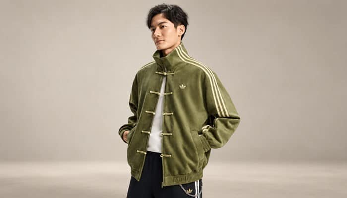 How to Style the Adidas Chinese New Year Jacket - Startup Editor | Startup Editor Man wearing an olive-green Adidas Chinese New Year Jacket with a relaxed fit, embroidered Trefoil, white 3-Stripes and traditional knot closures.