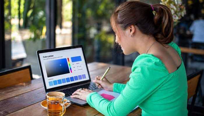 Google Color Picker for Social Media Graphics - Startup Editor | Startup Editor Woman using Google Color Picker on a laptop to compare blue shades and select a precise color code for a creative design project.