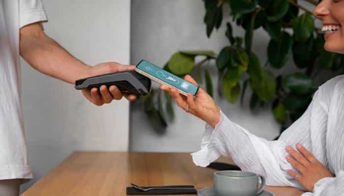 Contactless Payment for Small Businesses - Startup Editor | Startup Editor Contactless Payment at a café using a smartphone and handheld payment terminal for a convenient NFC tap-to-pay purchase.