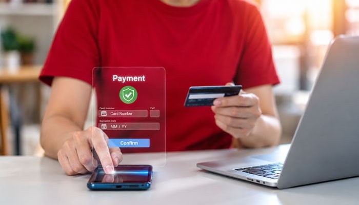 Can a Spiff Affect Overtime Pay? - Startup Editor | Startup Editor Person using a smartphone and bank card with a digital payment confirmation screen, illustrating electronic Spiff Payment processing.