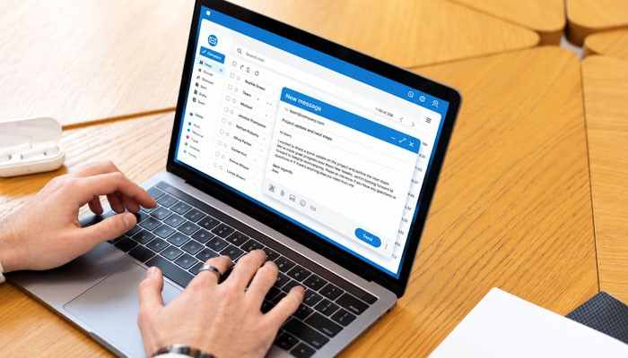 25 Professional Business Email Endings With Examples - Startup Editor | Startup Editor Person typing on a laptop with an email draft open, illustrating how to end a business email using professional closing phrases.