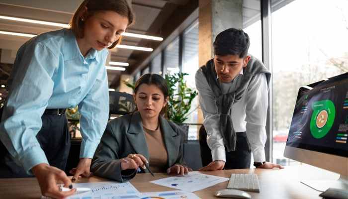 Can Bootstrapped Startups Qualify? - Startup Editor | Startup Editor HubSpot for Startups team reviewing customer data, sales analytics, and business performance on a desktop computer in a modern startup office.