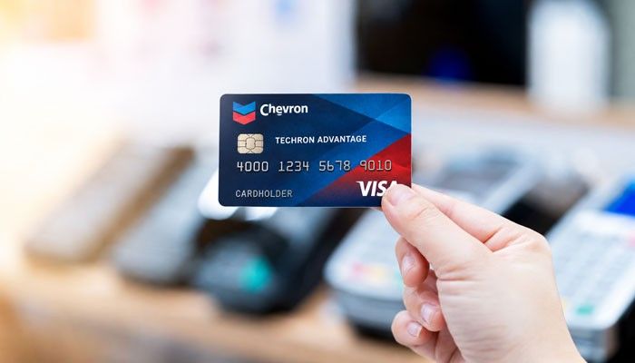 Chevron Credit Card Fees - Startup Editor | Startup Editor Close-up of a Chevron Credit Card Techron Advantage Visa held near a payment terminal, showing its use for purchases and cardholder benefits.