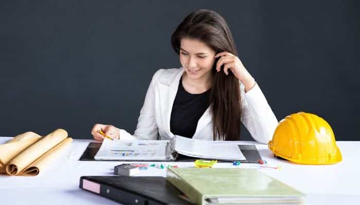 What Types of Workers Can Be 1099 Contractors? - Startup Editor | Startup Editor What Is a 1099 Employee example showing an independent professional reviewing project documents and paperwork at a desk with work equipment.