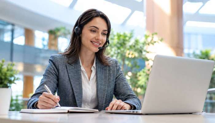 What Is the Fastest Way to Contact BHN Customer Service? - Startup Editor | Startup Editor BHN Customer Service agent wearing a headset while using a laptop and taking notes during a customer support inquiry.